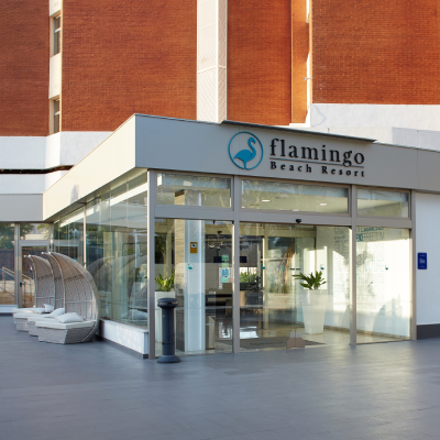 Entrada del Flamingo Beach Resort con fachada y letras luminosas.