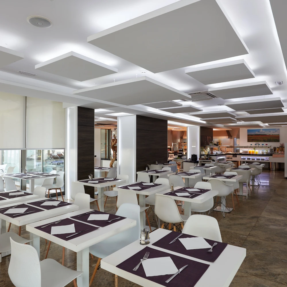 Comedor de hotel con mesas servidas y l&aacute;mparas de techo, estilo moderno.