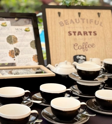 Tazas de caf&eacute; sobre mesa con carteles &ldquo;BEAUTIFUL STARTS&rdquo; y &ldquo;Coffee&rdquo;.
