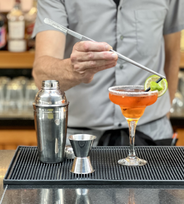 Barman prepara un c&oacute;ctel con hielo en un vaso tipo copa.