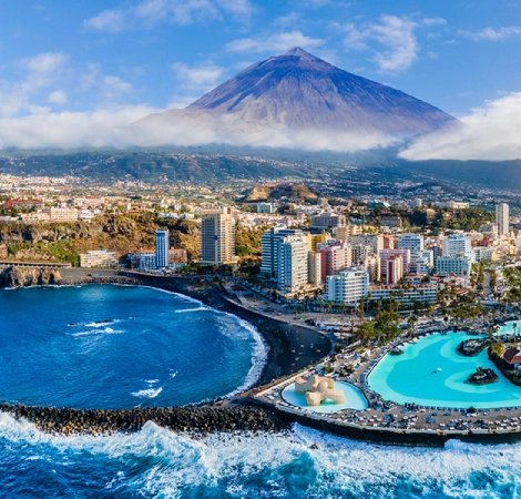 Vista a&eacute;rea de playa y ciudad con el volc&aacute;n Teide al fondo