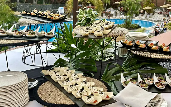 Mesa de buffet con mariscos y ensaladas junto a piscinas en un hotel