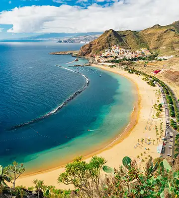 Playa y acantilados costeros con agua turquesa y sendero junto al mar.