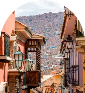 Calle estrecha con faroles y vista a una ciudad al fondo.
