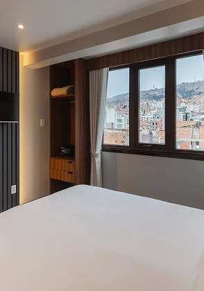 Dormitorio moderno con cama blanca y ventana con vista urbana