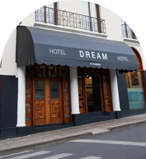 Entrada de hotel con toldo y puertas marrones, letrero &ldquo;HOTEL DREAM&rdquo;.