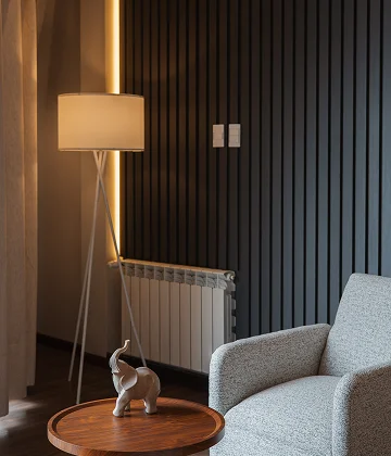L&aacute;mpara de pie y sof&aacute; gris junto a radiador en sala moderna.