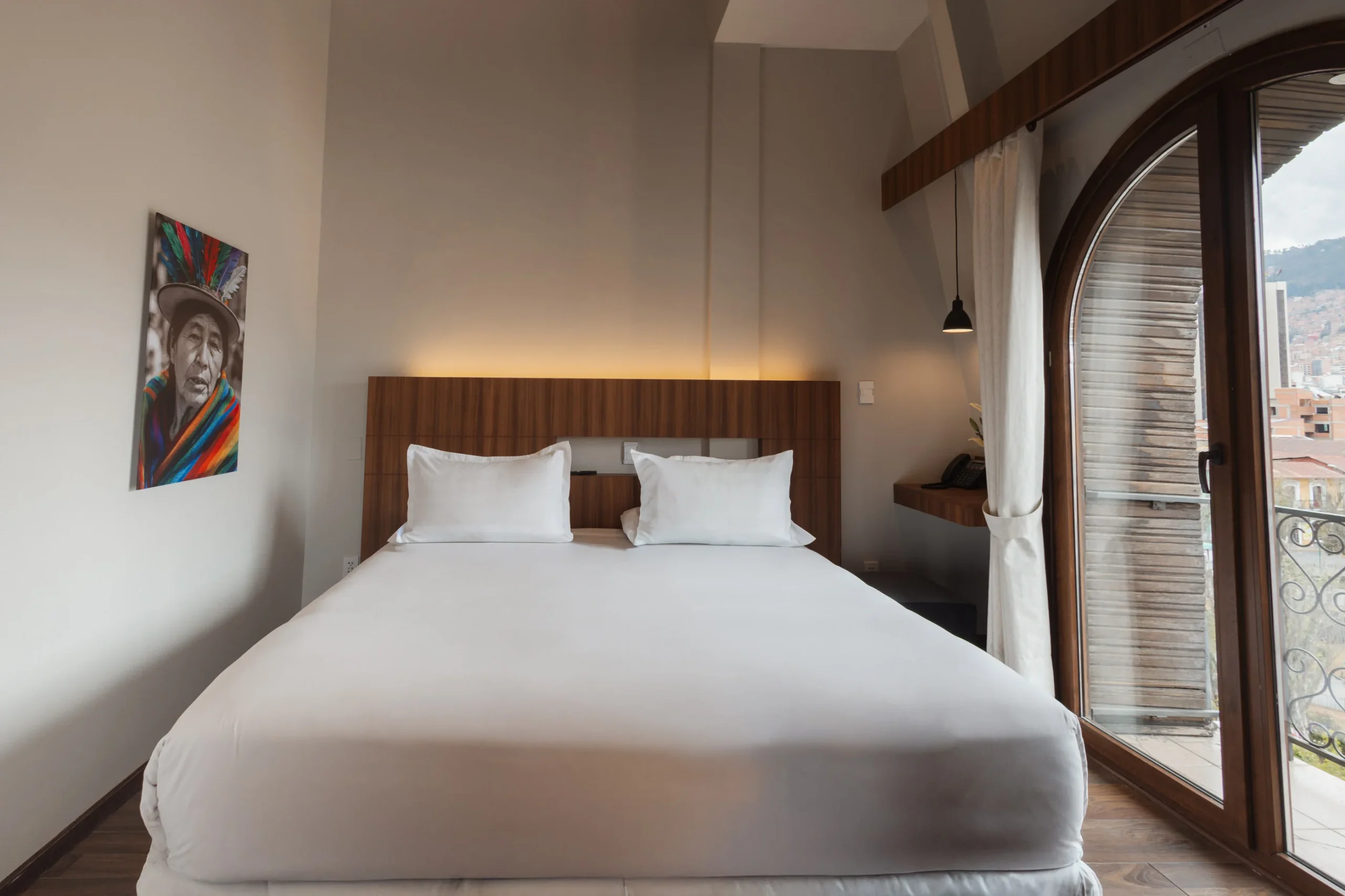 Dormitorio moderno con cama, cuadros y ventanal con cortinas blancas