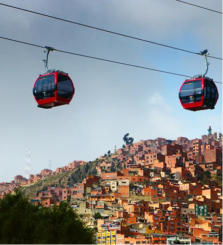 Telef&eacute;ricos rojos sobre una ciudad monta&ntilde;osa con casas de colores al fondo