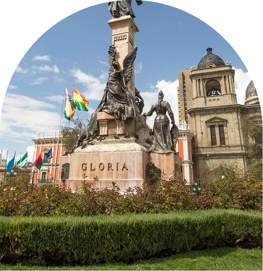 Estatua &ldquo;Gloria&rdquo; frente a una iglesia con banderas y jard&iacute;n.