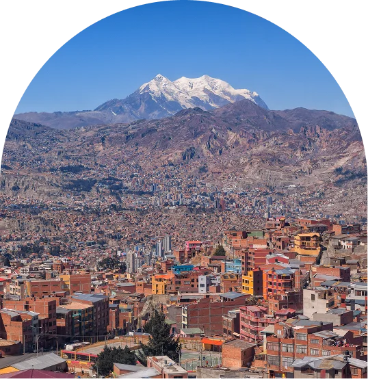 Ciudad andina con monta&ntilde;as nevadas al fondo bajo cielo despejado.