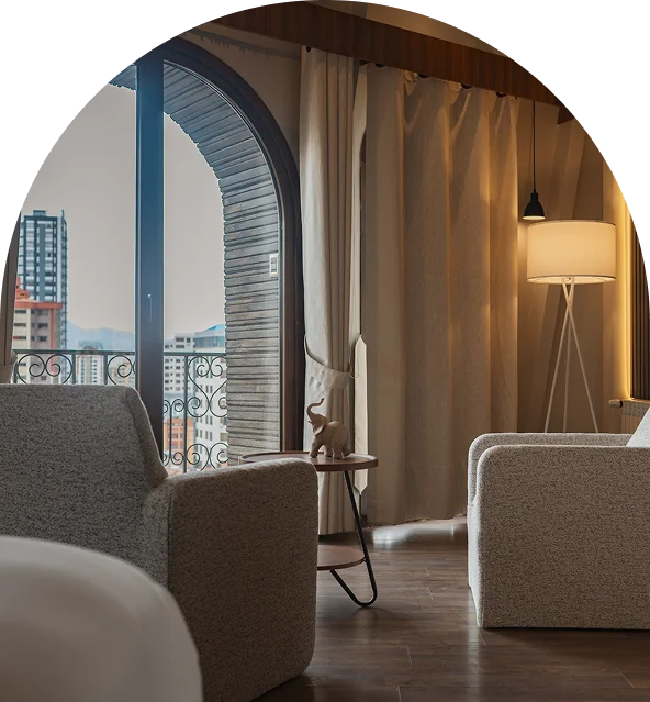 Sala moderna con sof&aacute; gris, cortinas y una l&aacute;mpara junto a una ventana
