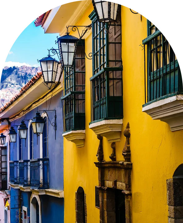Calle con casas amarillas y balcones con faroles, estilo espa&ntilde;ol.