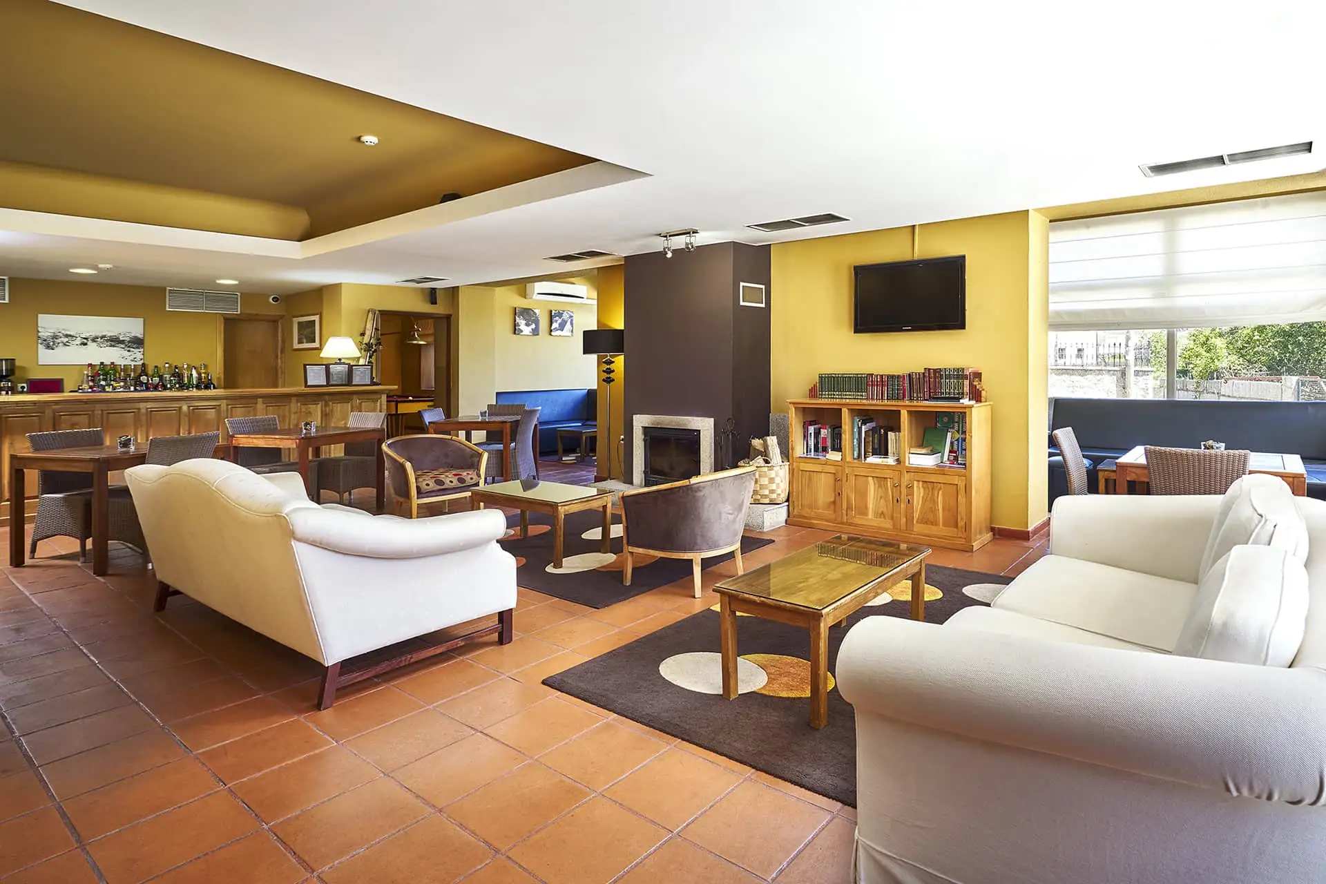 Sala de estar acolhedora com sof&aacute;s, lareira, bar e mesa de madeira