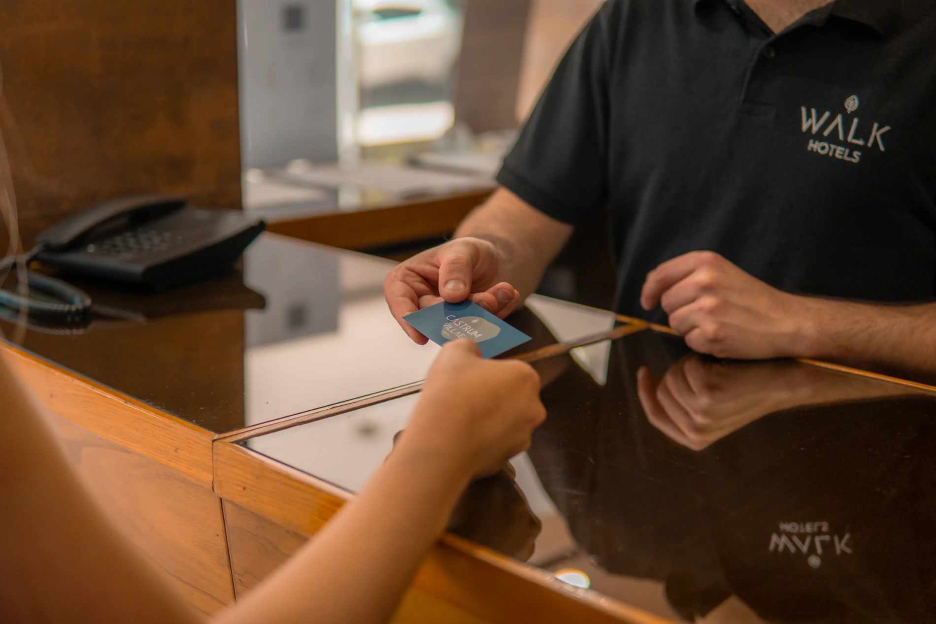 Funcion&aacute;rio do hotel entrega cart&atilde;o de check-in ao h&oacute;spede no balc&atilde;o