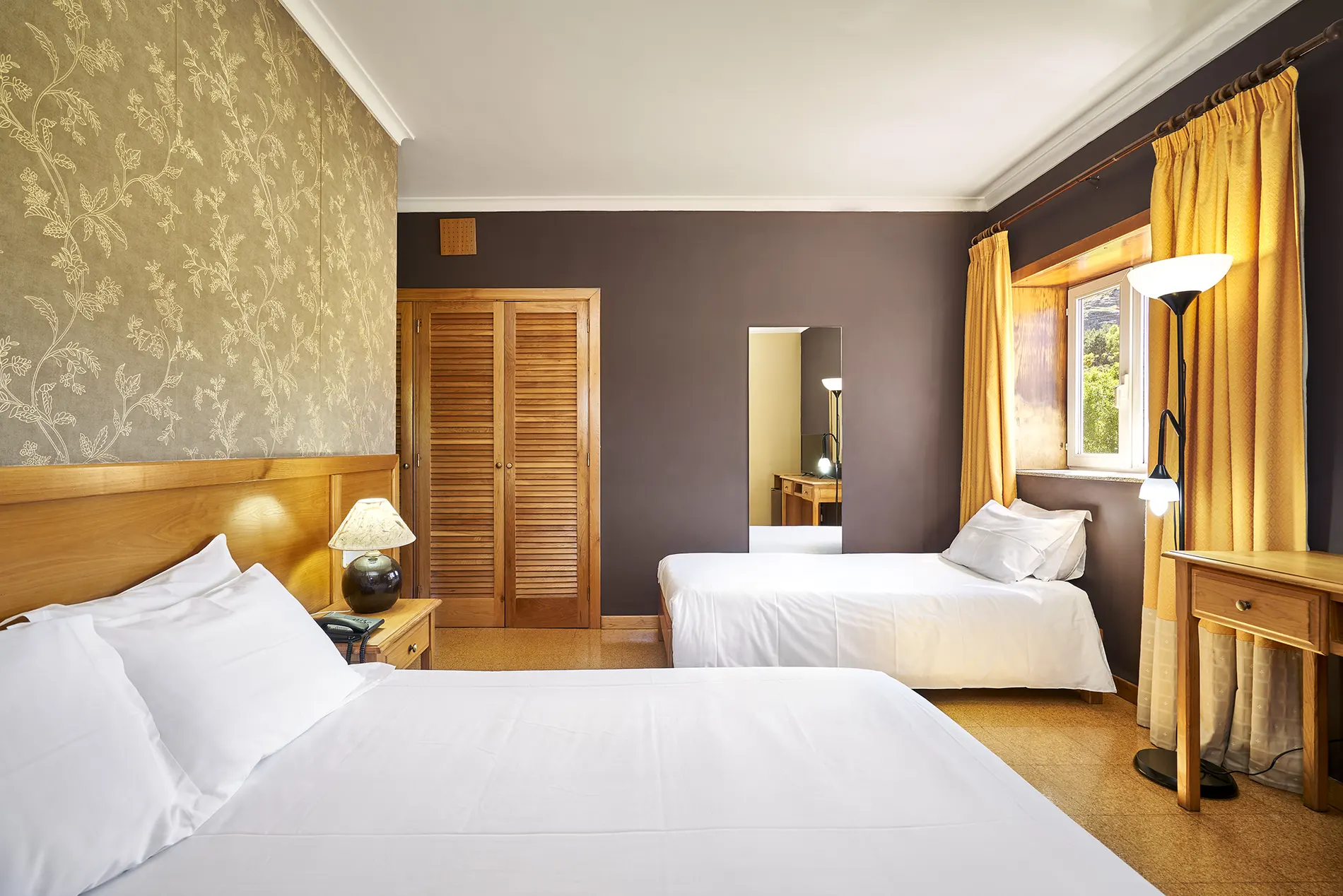 Quarto com duas camas, cortinas amarelas e armário de madeira