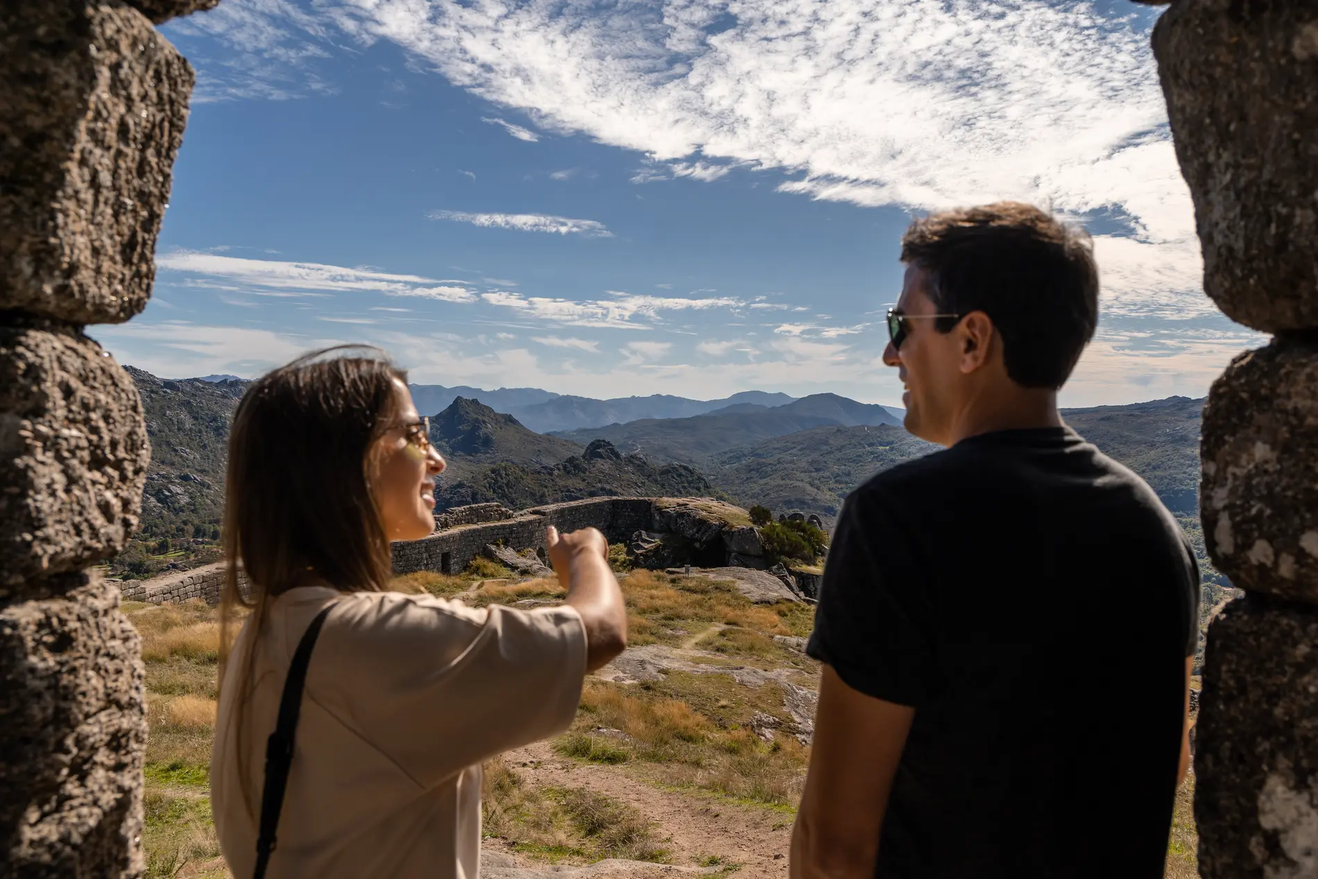 Casal observa montanhas e céu azul em passeio turístico ao ar livre