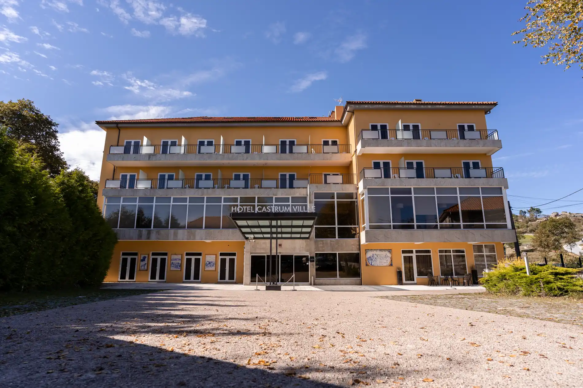 Fachada do Hotel Castrum Vilafe, prédio amarelo sob céu azul