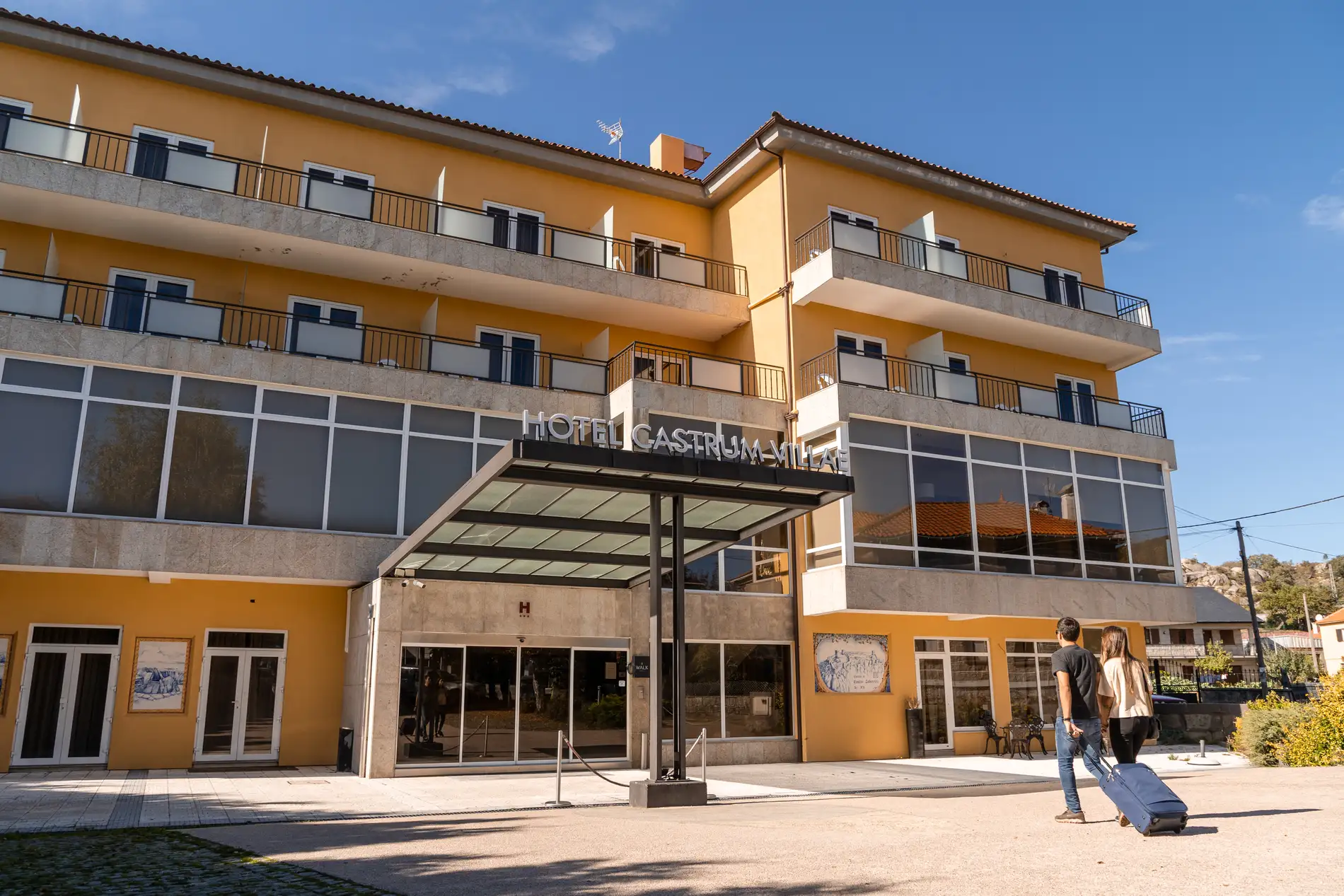 Fachada do Hotel CastruM Villa, com varanda e entrada sob céu azul