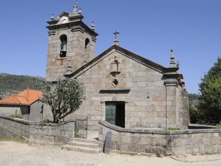 Igreja de pedra com torre e cruzes sob c&eacute;u azul
