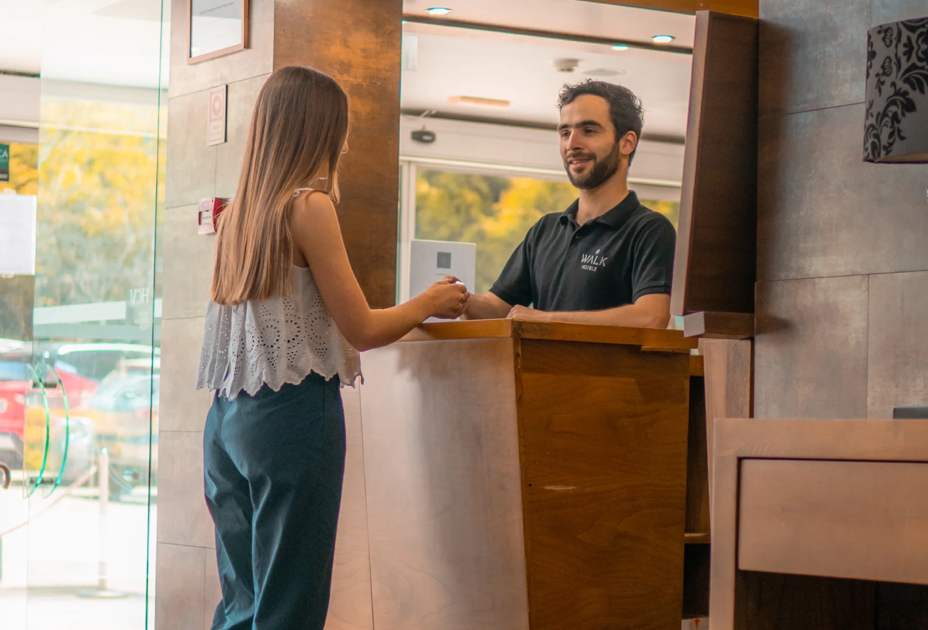 Recepcionista entrega chave a h&oacute;spede no balc&atilde;o do hotel