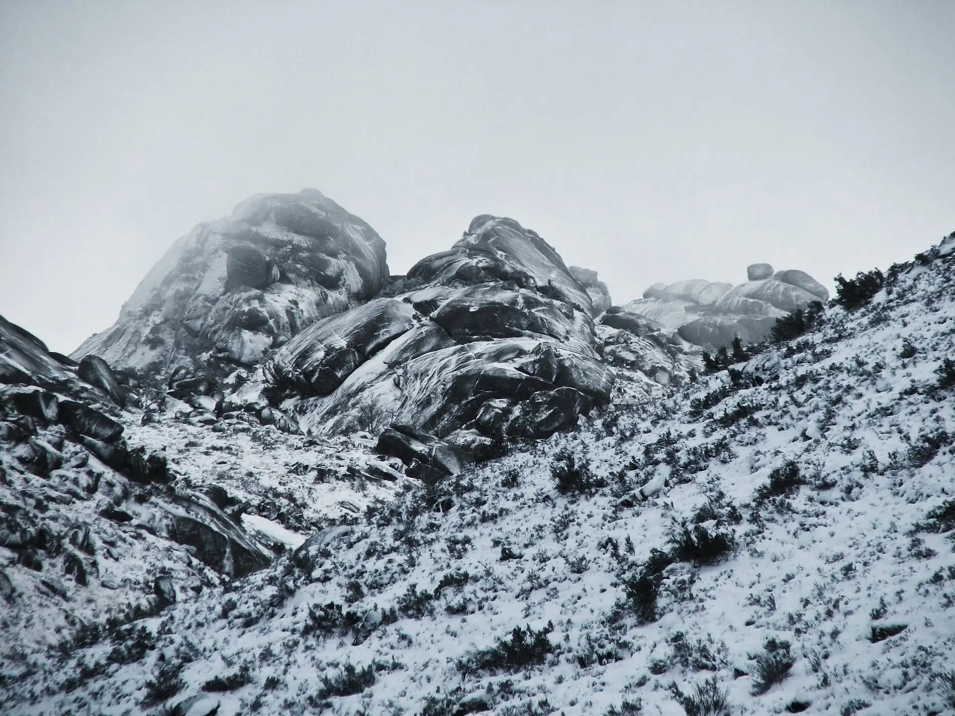 Estátuas gigantes de metal em colinas cobertas de neve, sob céu nublado