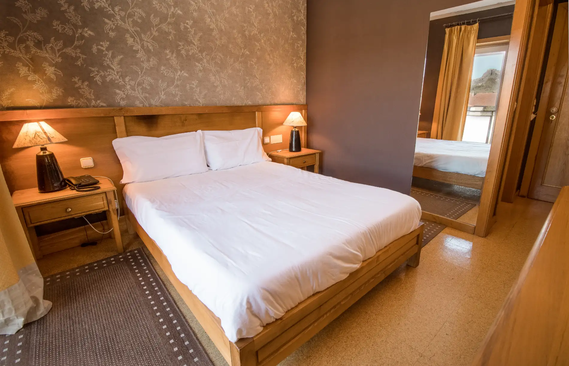 Quarto de hotel com cama de casal e cortinas amarelas, ilumina&ccedil;&atilde;o quente
