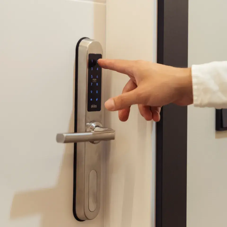 Mano introduciendo c&oacute;digo en cerradura digital con teclado y picaporte met&aacute;lico
