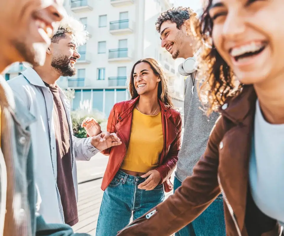 Grupo de amigos riendo al aire libre, con edificios de fondo