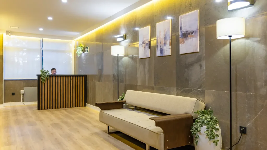 Recepci&oacute;n moderna con mostrador de madera, sof&aacute;s y cuadros iluminados