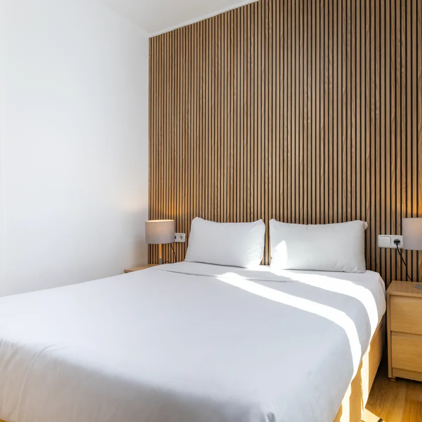 Dormitorio moderno con cama doble y cabecero de madera a rayas