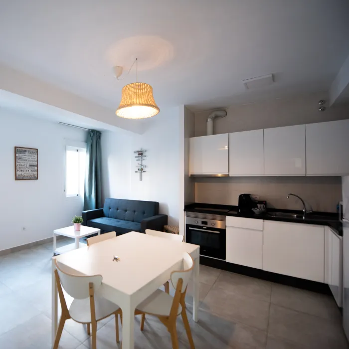 Sala y cocina modernas con mesa, sillas y l&aacute;mpara de techo de mimbre