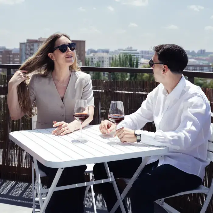 Pareja brindando en terraza con dos copas de vino al aire libre