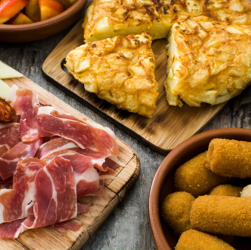 Pechuga de pollo horneada y queso en porciones, con jam&oacute;n y croquetas doradas.