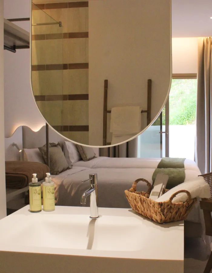 Ba&ntilde;o moderno con lavamanos blanco, espejo grande y ducha de vidrio.