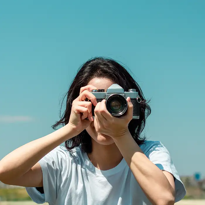 Mujer con c&aacute;mara fotogr&aacute;fica vintage, tomando una foto al aire libre