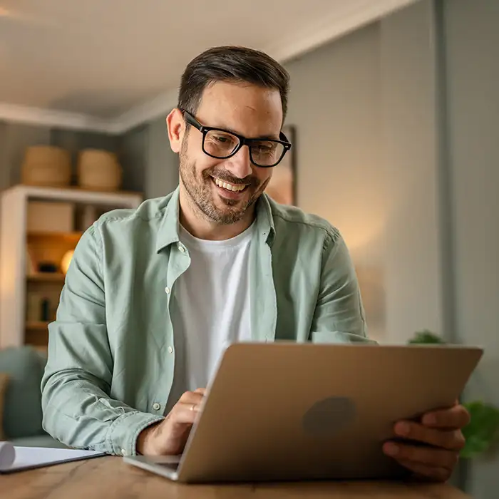 Hombre con gafas sonr&iacute;e leyendo en una tablet en casa