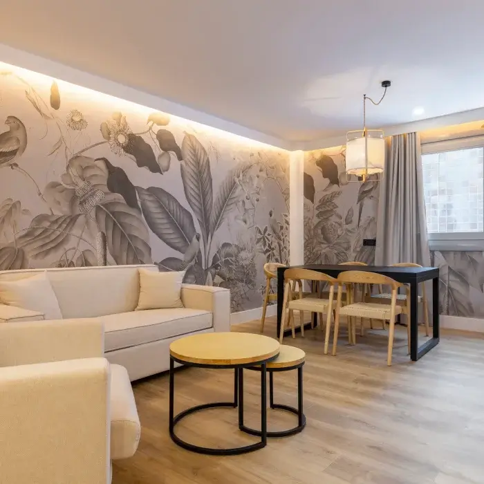Sala de estar moderna con sof&aacute;, mesa redonda, sillas y mural floral en pared