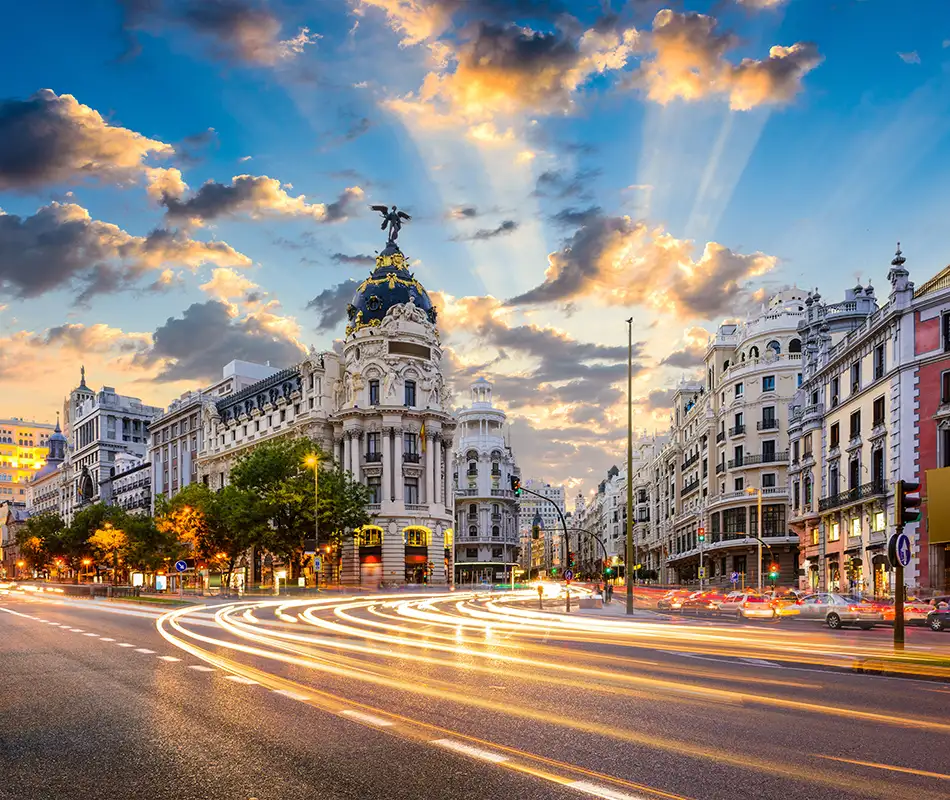 Vista nocturna de la Gran V&iacute;a de Madrid con luces y el monumento en la plaza