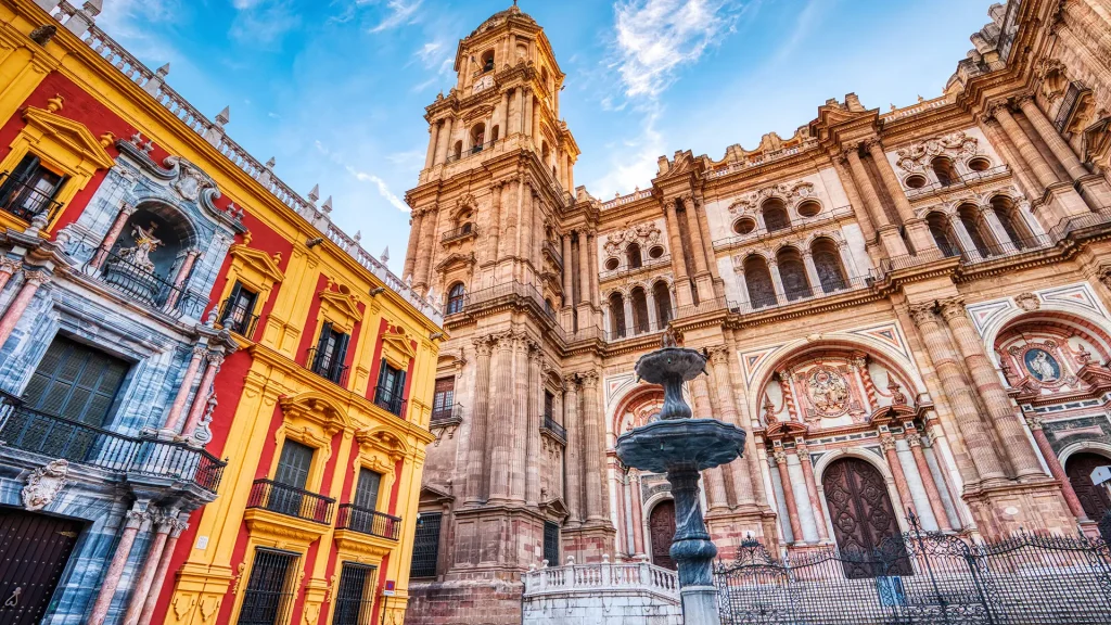 Catedral de Sevilla con torre y fuente, edificios coloridos y cielo azul