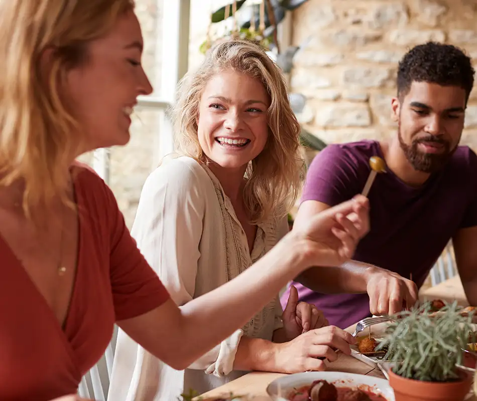 Familia riendo en una comida, compartiendo platos en la mesa al aire libre