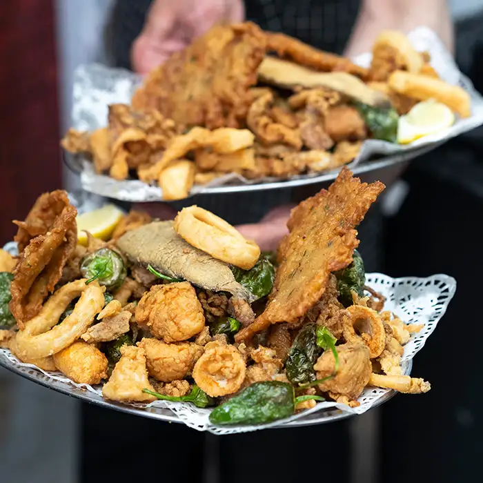 Bandeja con carne frita y alitas, papas y verduras, servida en mesa