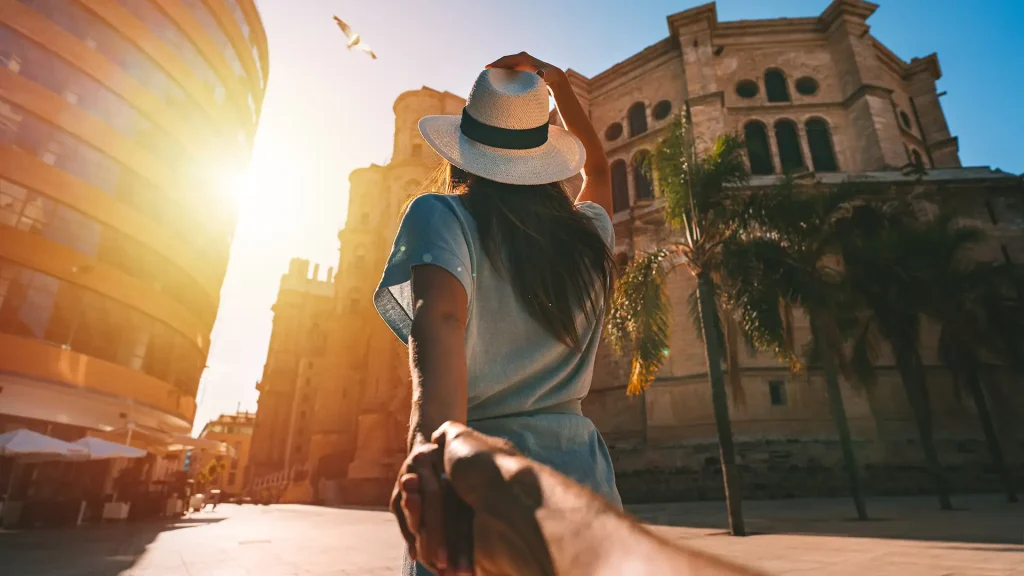 Mujer con sombrero camina frente a un edificio hist&oacute;rico al atardecer