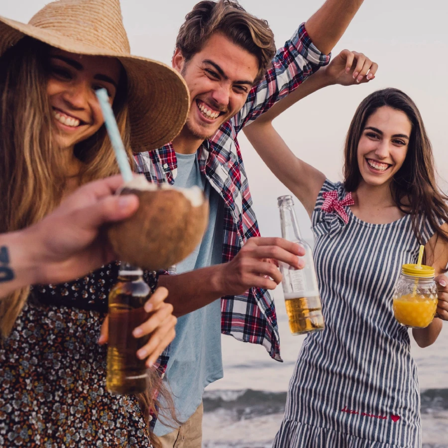 Grupo de amigos con bebidas y sonrisas en una reuni&oacute;n al aire libre.