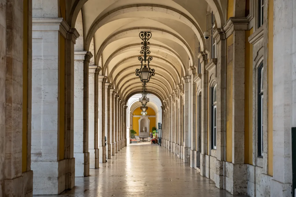 Galeria com arcos e l&acirc;mpadas ornamentais em corredor de m&aacute;rmore, perspectiva.