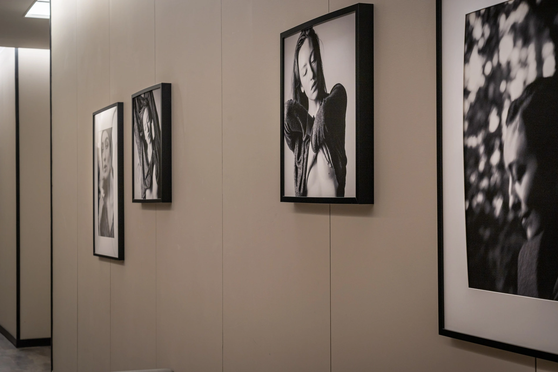 Galeria com fotos em preto e branco em molduras pretas nas paredes.
