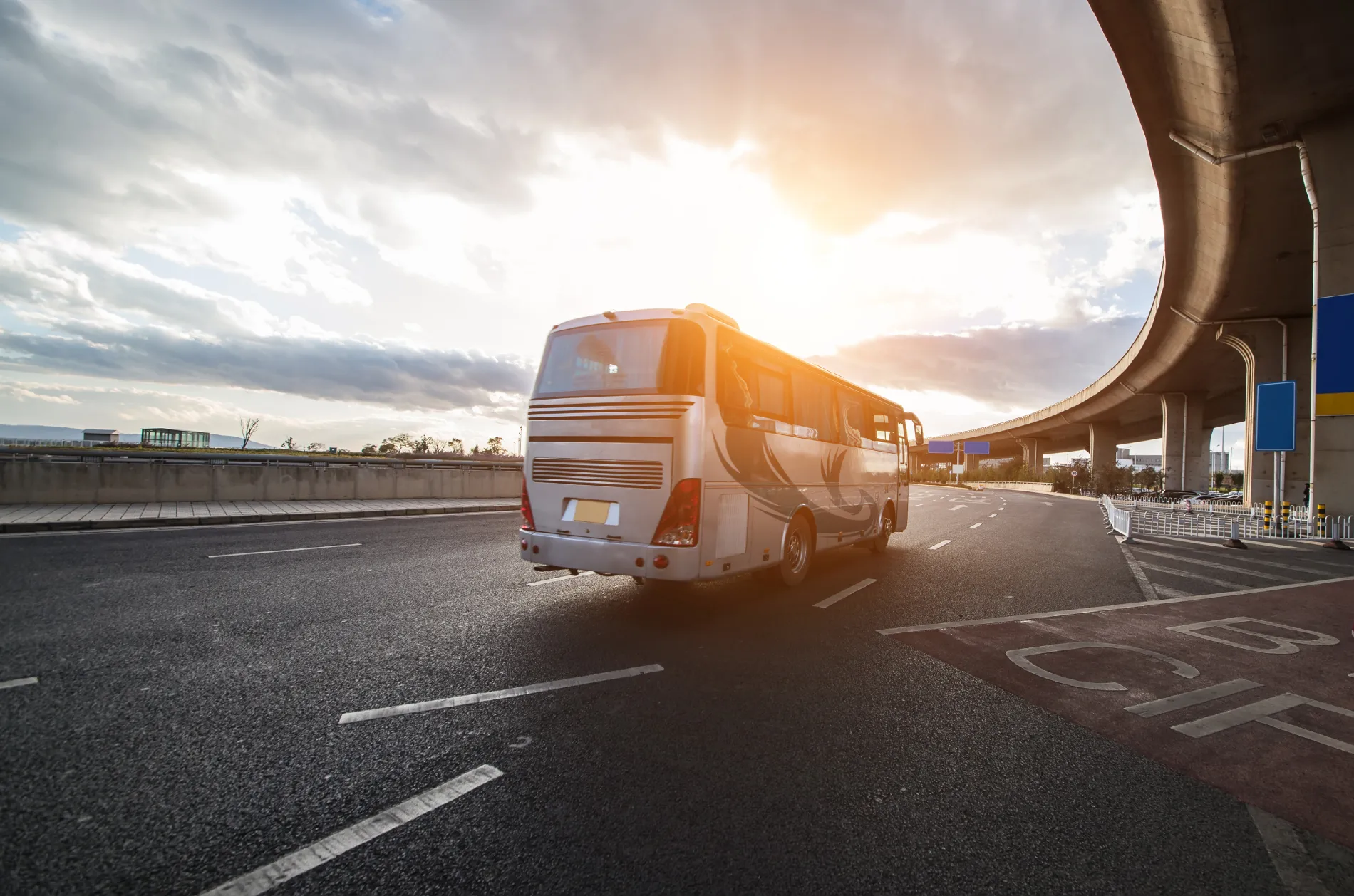 &Ocirc;nibus amarelo em rodovia sob o p&ocirc;r do sol, em viaduto elevado