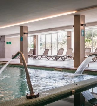 Piscina interior con tumbonas y luz de techo, gimnasio termal.