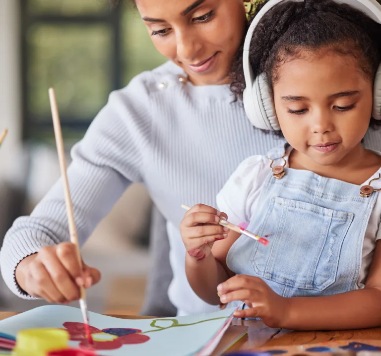 Madre e hijo pintando con pinceles, con el peque&ntilde;o usando aud&iacute;fonos