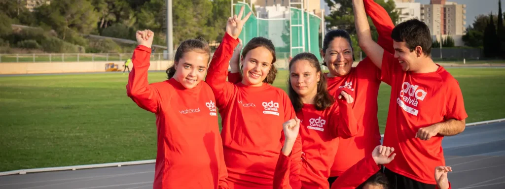 Equipo joven con camisetas rojas celebra en pista deportiva al aire libre